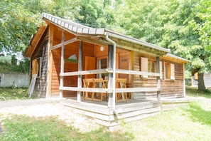 Een houten chalet met een veranda, een tafel en stoelen.