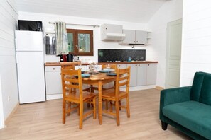 Une cuisine compacte comprenant une table à manger, des chaises, un réfrigérateur et un canapé vert.