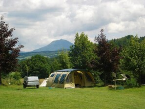 A camping site with a tent, a vehicle, and a mountain in the background. - Camping 3 étoiles - ccbgcfh (Saint-Bonnet-près-Orcival)