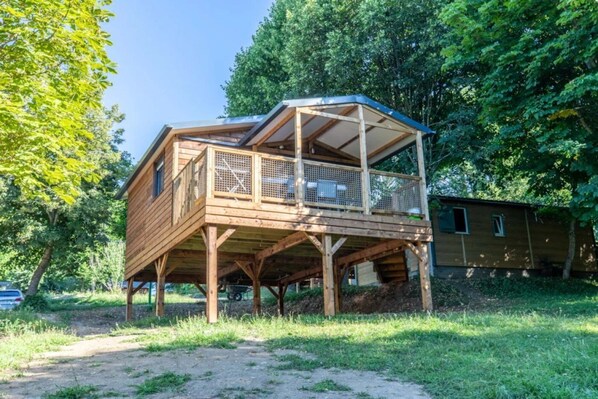 Een houten chalet met een balkon, omgeven door bomen.