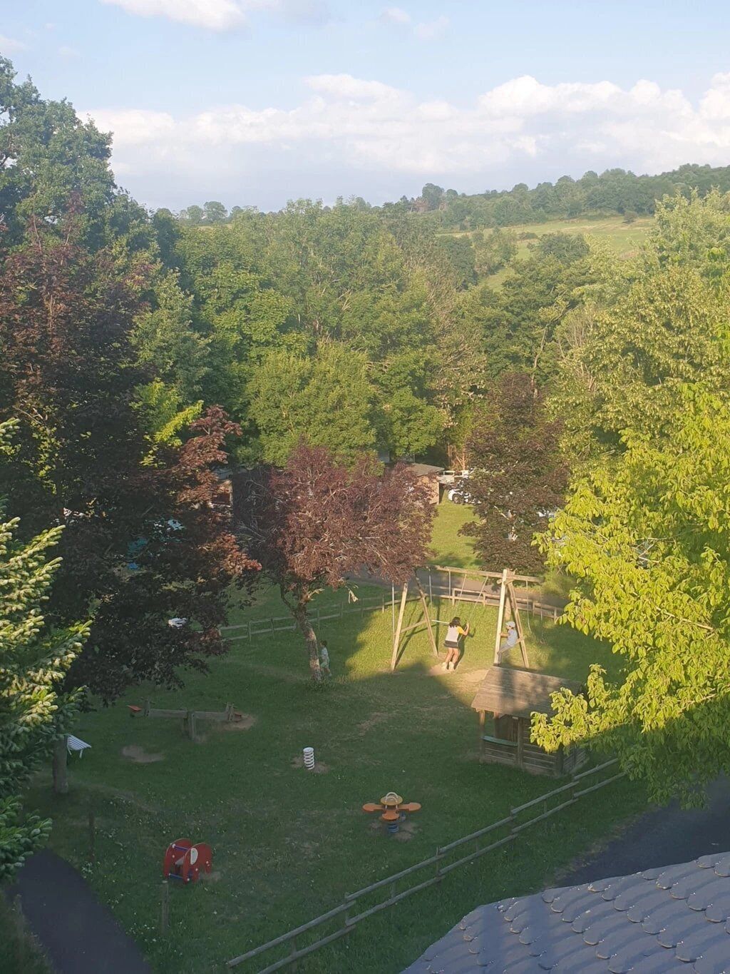 A park with a swing set, a red exercise machine, and a grassy area.