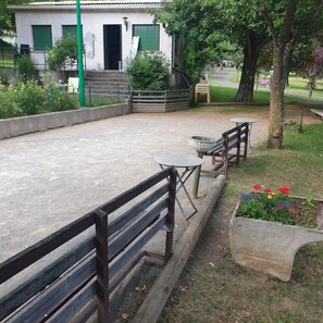 A courtyard with a concrete floor, a wooden bench, a small round table, and a planter with flowers. - Camping 3 étoiles - ccbgcga (Saint-Bonnet-près-Orcival)