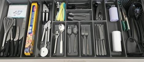 Un tiroir compartimenté contenant divers ustensiles de cuisine et une boîte à pain.