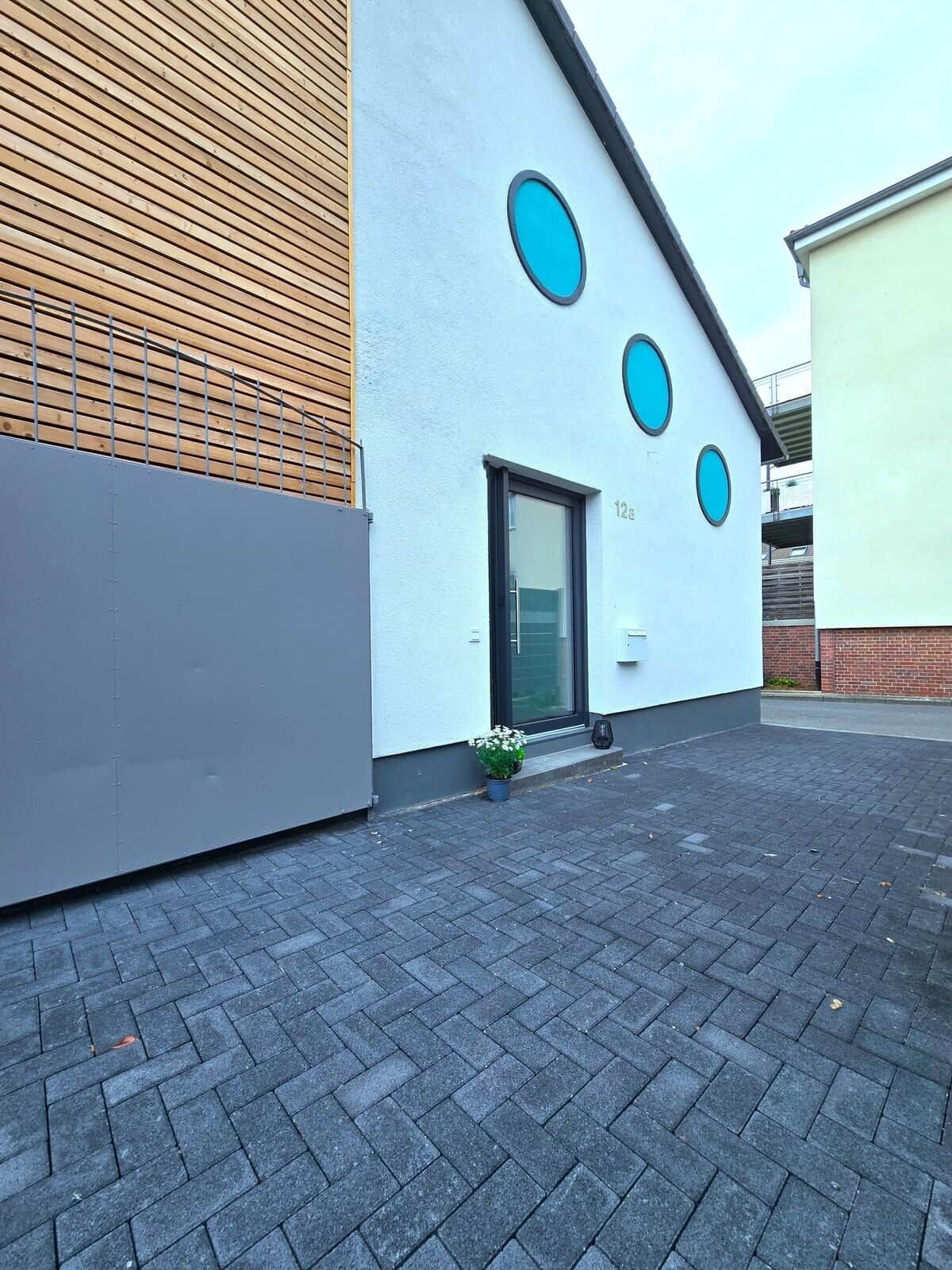 Un bâtiment moderne doté d’un toit plat, d’une grande fenêtre et d’une porte.