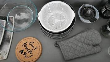 A kitchen with a coffee maker, a kettle, a tea kettle, a glass container, a cloth, and a coaster with text.