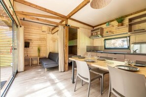 A wooden interior with a dining area, sofa, and kitchen. - Chalet 3 étoiles - ccbgbfi (Saint-Bonnet-près-Orcival)