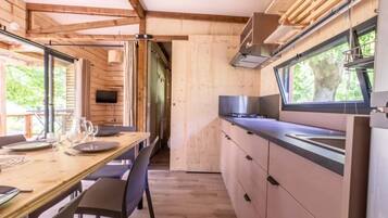 Une cuisine compacte aux murs en bois, un coin repas avec une table et des chaises, et une fenêtre qui laisse entrer la lumière naturelle.