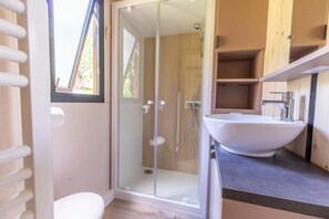 Une salle de bain moderne avec une douche à parois de verre, un lavabo blanc et des meubles en bois.
