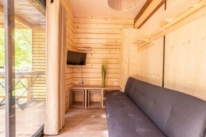 Ein Holzinterieur mit einer Couch, einem Flachbildfernseher und einem kleinen Tisch.