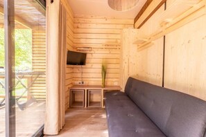 Un intérieur en bois avec un canapé, un téléviseur à écran plat et une petite table.
