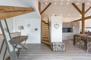 Et moderne interiør med en trætrappe, et skrivebord med lampe, en hjerteformet pynteting og et tekøkken.