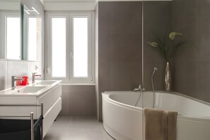 Ein modernes Badezimmer mit einer großen Badewanne, einem Doppelwaschbecken und einem Spiegel.