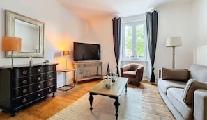 Ein Wohnzimmer mit Fernseher, einer Couch, einem Couchtisch und einer Kommode.