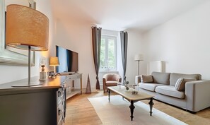 Ein modernes Wohnzimmer mit Fernseher, Sofa, Couchtisch und Lampe.