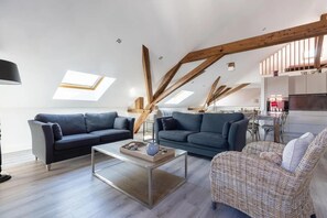 En moderne loftlejlighed med synlige træbjælker, spiseplads og et køkken.