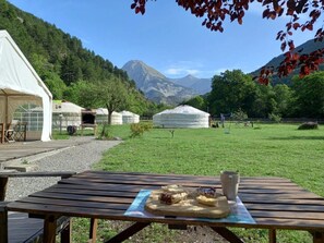 Jurten in einem grasbewachsen Feld, im Hintergrund Berge.