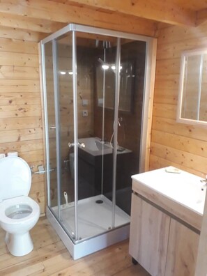 A wooden cabin bathroom with a glass-enclosed shower, a toilet, and a sink. - Chalet 3 étoiles - ccbgche (Prads-Haute-Bléone)