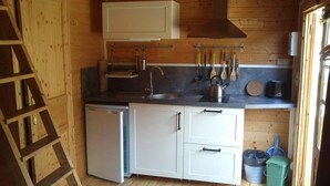 Uma cozinha compacta com armários brancos, uma pia e um fogão.