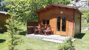 Une cabane en bois avec une terrasse, une table à manger et des chaises.