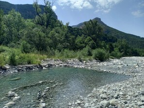 A river with clear water, surrounded by rocky terrain and dense greenery. - Chalet 3 étoiles - ccbgcgf (Prads-Haute-Bléone)