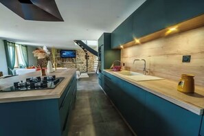 A modern kitchen with a central island, a built-in stove, and a wooden backsplash. - La Belle Aire, at Christophe's (Le Fœil)