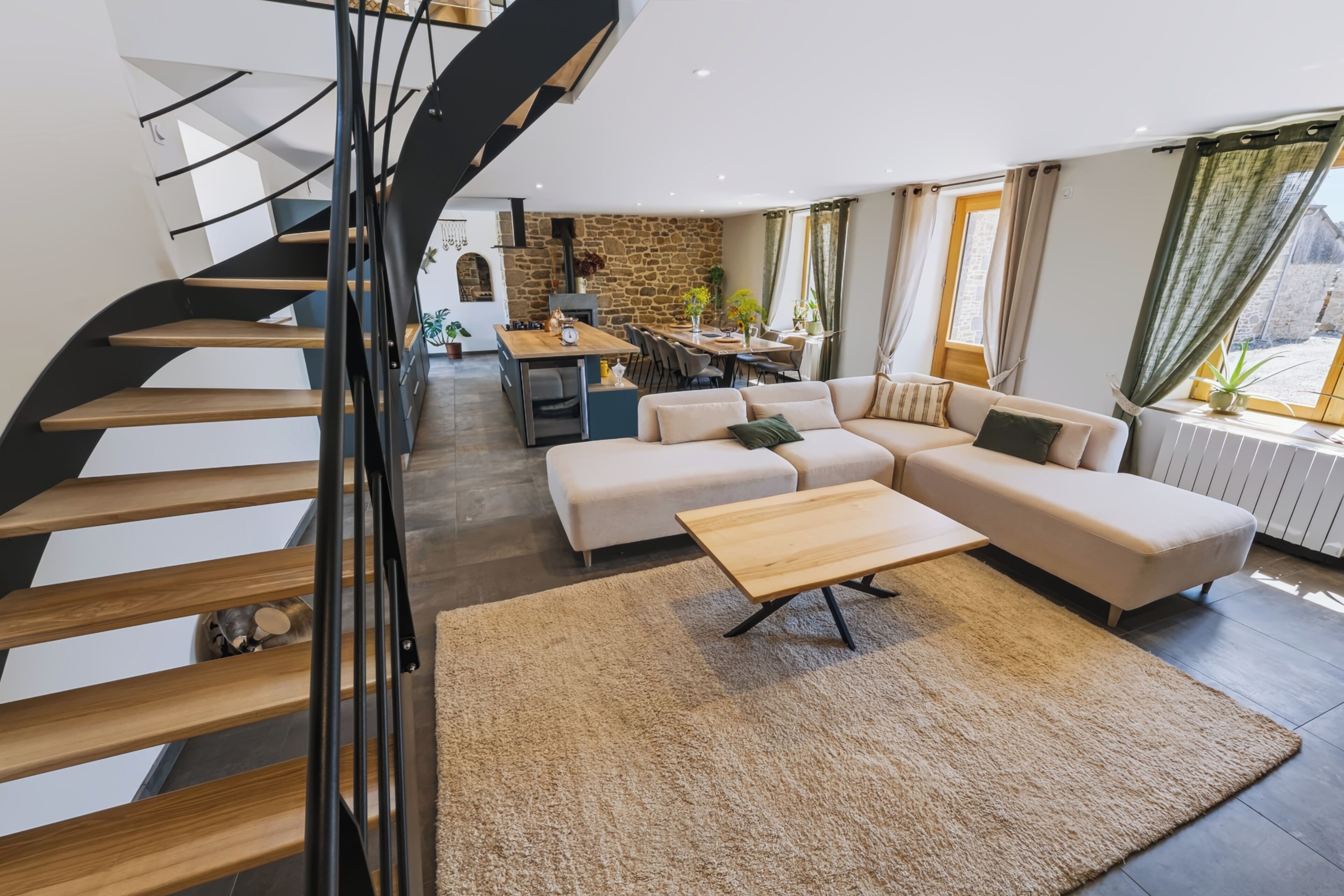 En moderne stue med sofa, sofabord og en spiralformet trappe.