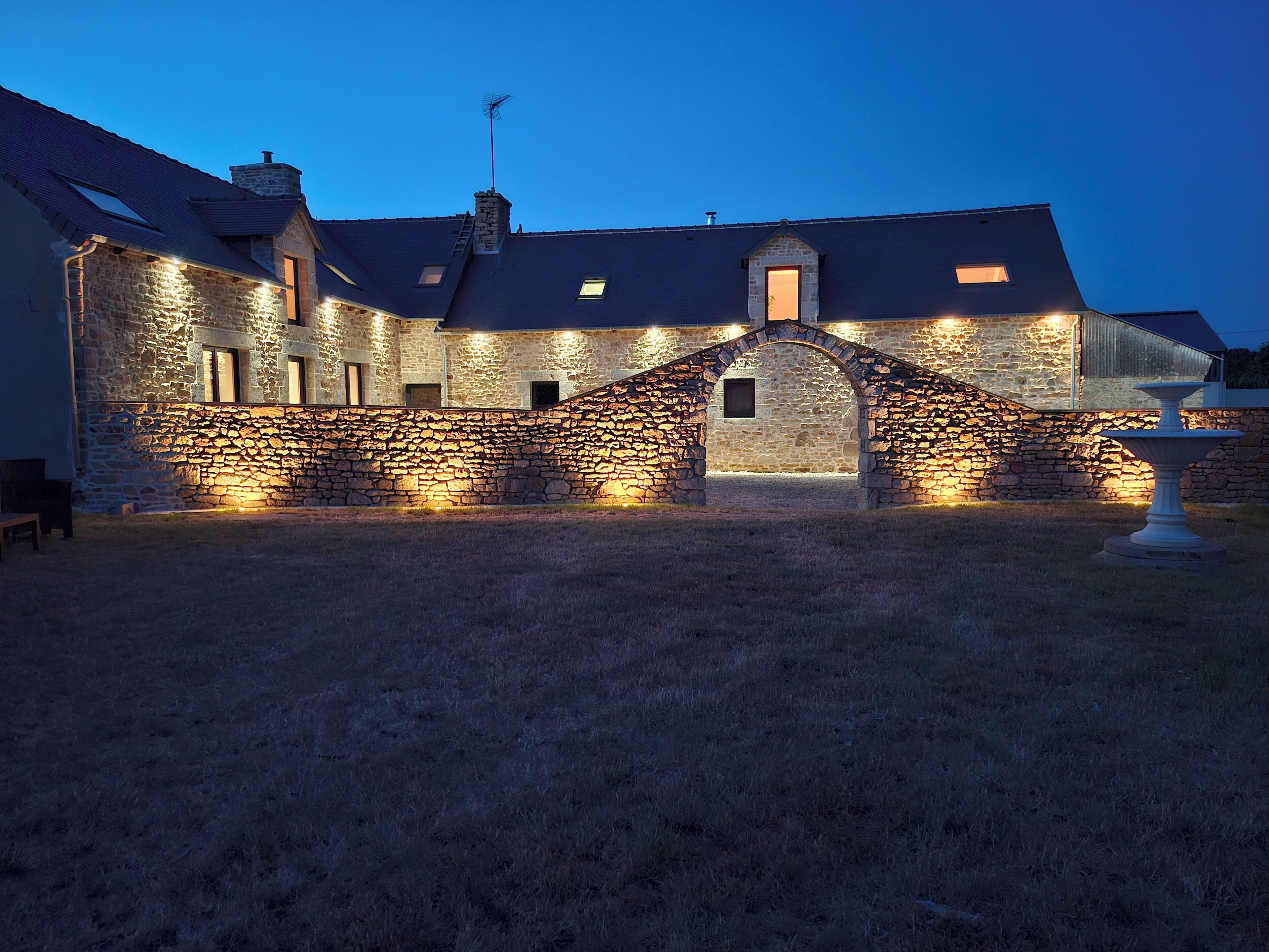 A stone building with a central archway, multiple windows, and a chimney.