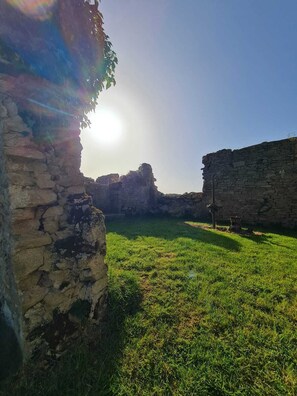 An ancient stone structure with a grassy courtyard and a clear sky.