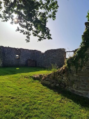 A stone building with a grassy courtyard, a wooden door, and a tree overhead. - La Belle Aire, at Christophe's (Le Fœil)