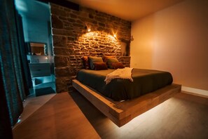 A bedroom with a stone wall, a wooden bed frame, and a nightstand. - La Belle Aire, at Christophe's (Le Fœil)