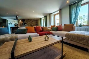 A modern living room with a sofa set, a coffee table, and a kitchen area visible in the background. - La Belle Aire, at Christophe's (Le Fœil)
