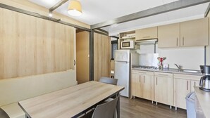 Une cuisine moderne avec des meubles en bois, une table à manger, des chaises, un four à micro-ondes, un réfrigérateur et une cuisinière.