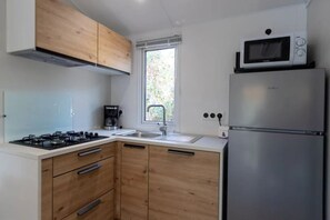 Eine kompakte Küche mit Gasherd, Kaffeemaschine, Mikrowelle und Kühlschrank.