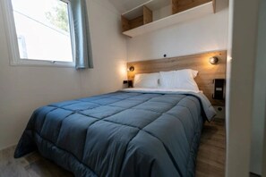 Ein Schlafzimmer mit Bett, Fenster und Holzboden.