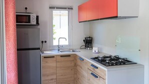 A compact kitchen with a microwave, sink, and stove. - Camping 3 étoiles - Piscine  - ccbgebe (Pianottoli-Caldarello)