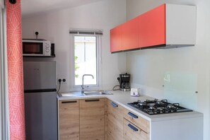 A compact kitchen with a microwave, sink, and stove. - Camping 3 étoiles - Piscine  - ccbgebe (Pianottoli-Caldarello)