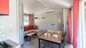 A compact living space with a dining table, seating area, and kitchenette. - Camping 3 étoiles - Piscine  - ccbgebe (Pianottoli-Caldarello)
