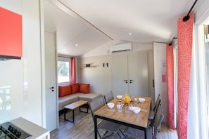 A compact living space with a dining table, seating area, and kitchenette. - Camping 3 étoiles - Piscine  - ccbgebe (Pianottoli-Caldarello)