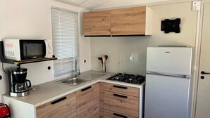 A compact kitchen with a microwave, coffee maker, sink, stove, and refrigerator. - Camping 3 étoiles - Piscine  - ccbgebg (Pianottoli-Caldarello)