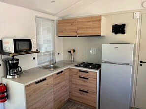 Eine kompakte Küche mit Mikrowelle, Kaffeemaschine, Spüle, Herd und Kühlschrank.