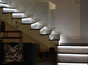 Eine Treppe mit integrierter Beleuchtung, ein Sofa mit floralem Muster und ein kleiner Tisch mit einer Vase.