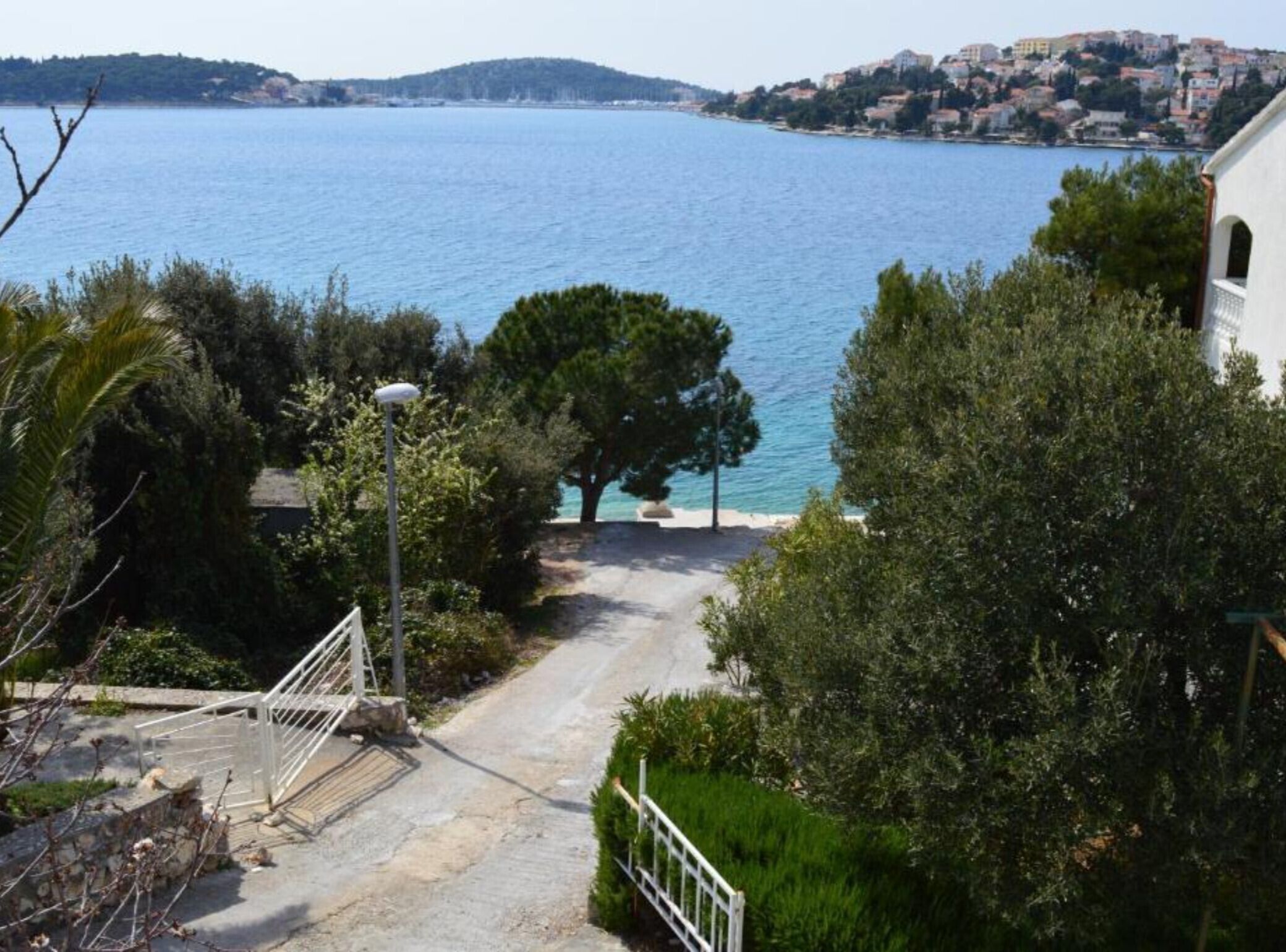 Un sentier côtier qui mène à un plan d’eau et offre une vue sur une ville située au loin.