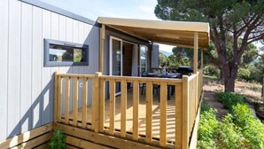 A wooden deck with a view of a natural landscape, a window, and a door leading to an outdoor area. - Camping 3 étoiles - Piscine  - ccbgebh (Pianottoli-Caldarello)