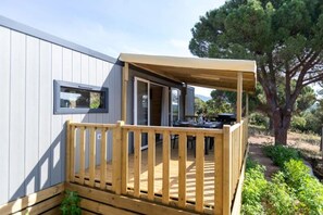 Eine Holzterrasse mit Blick auf eine natürliche Landschaft, ein Fenster und eine Tür zu einem Außenbereich.