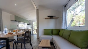 A modern living room with a sofa and a dining area with a table and chairs. - Camping 3 étoiles - Piscine  - ccbgebh (Pianottoli-Caldarello)