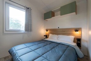Ein Schlafzimmer mit Bett, einem Vorhangfenster und Wandleuchten.