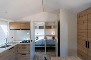 A compact room with a kitchenette, a bed, and a wooden wardrobe. - Camping 3 étoiles - Piscine  - ccbgebi (Pianottoli-Caldarello)