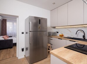 A compact kitchen with a stainless steel refrigerator, a microwave, and a wooden countertop. - One Bedroom Apartment with Terrace and SeaView(A3) (Omis)
