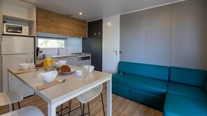 Een kleine keuken met een eethoek, een blauwgroene bank en een magnetron.