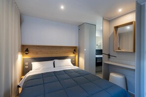 A modern hotel room with a large bed, a wooden headboard, bedside lamps, a built-in wardrobe, and a mirror on the wall. - Camping 3 étoiles - Piscine  - ccbgeca (Pianottoli-Caldarello)